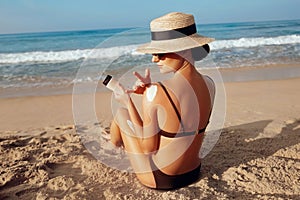 Sun Protection, girl using sunscreen to safe her skin healthy. Sexy young woman in bikini holding  bottles of sunscreen in her han