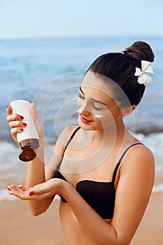 Sun Protection, girl using sunscreen to safe her skin healthy. Sexy young woman in bikini holding  bottles of sun cream in her han