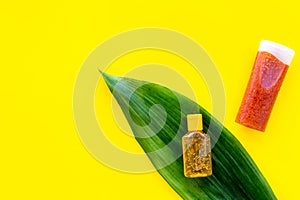 Sun protection products. Bottles with cream or lotion near palm leaves on yellow background top view copy space