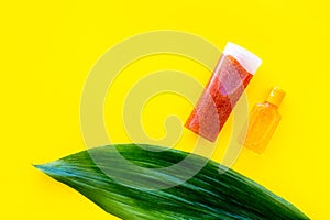 Sun protection products. Bottles with cream or lotion near palm leaves on yellow background top view copy space