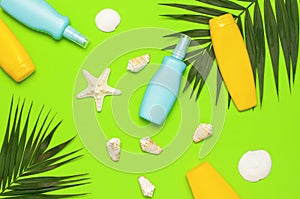 Sun protection Summer background vacation travel concept Yellow blue bottles of sunscreen cream tropical palm leaves shells