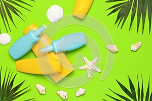 Sun protection Summer background vacation travel concept Yellow blue bottles of sunscreen cream tropical palm leaves shells