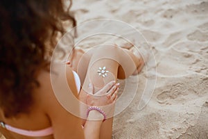 Sun protection sun cream, on her smooth tanned legs. Young beauty woman with sun shape on the leg.