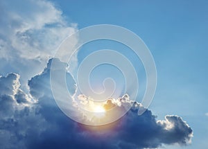 The sun and sun rays appearing from behind a great fluffy cloud
