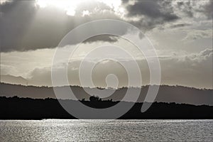 Sun rays bursting through clouds over coastal horizon