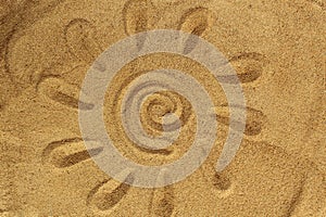 The sun with rays is drawn on the sand on the beach in summer.