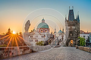 Sun rays filling the scene with colors during sunrise on empty deserted Charles bridge in Prague, Czech Republic