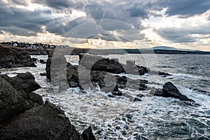 Sun rays through heavy clouds over Ships Rock formation in Sinemorets