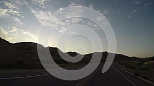 Sun rays over winding road through badlands