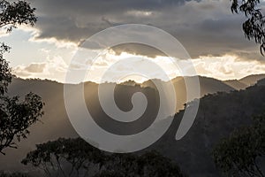 Sun rays peaking over a Southern Highland`s mountain range at sunset