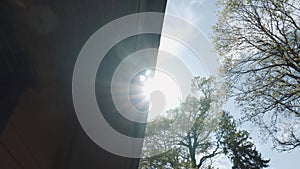 Sun rays shine brightly on edge of wooden gable roof with drain pipe.