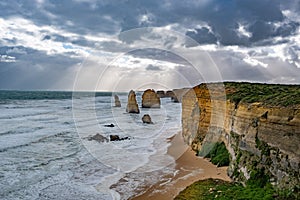 Sun rays shining through stormy clouds on the Twelve Apostles rock formations.