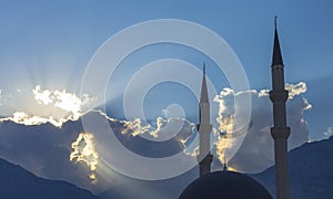 Sun rays through the sky illuminate mosque Kemer Cami