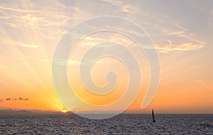 Sun rays at sunset with sailboat on the coast of Donostia, Cantabrico Sea.