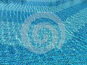 Sun reflections in a pool water above a blue pool tile