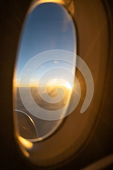 Sun rise from the window of an airplane seat. Sun is shining with a glare coming through the window glass.