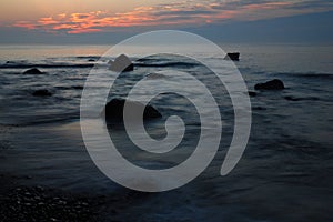 The sun rises along a rocky coast