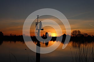 The sun rises over the water of the river Hollandsche IJssel near the dike at Park Hitland photo