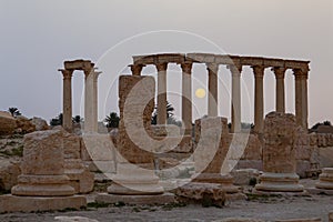 Sun rises between the stone pillars of the ancient ruins in Palmyra
