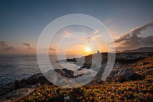 Sun rising behind genoese tower in Corsica