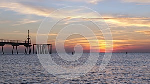 Sun is rising in the mediterranean sea with view to the pontoon and two buoys - Pont del Petroli, Badalona, Barcelona