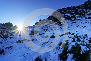 The sun rising between the mountains at sunrise, landscape with snow and rocks. Puerto de la Morcuera, Madrid photo