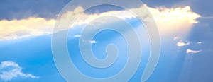 The sun`s rays break through the blue clouds. The background of the sky