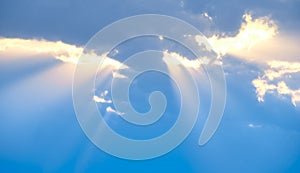 The sun's rays break through the blue clouds. The background of the sky.