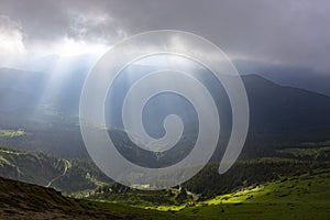 The sun`s rays break through the clouds on a background of mountains. Region Maramures Mountains, Mount Pip Ivan, Ukraine. Vibrant