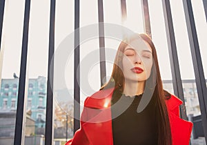 Sun`s rays are breaking through the back of engaging sweet lady in red coat and sun above her head