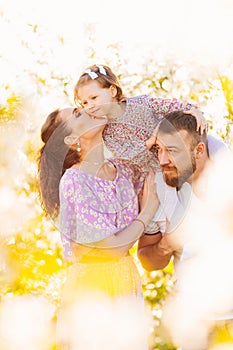 in the sun's rays. happy family in a blooming spring garden.