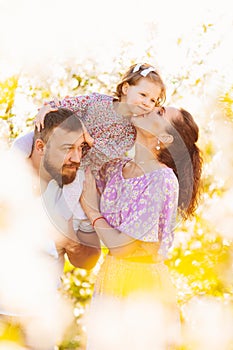 in the sun's rays. happy family in a blooming spring garden.