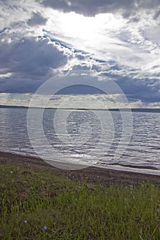 The sun`s rays make their way through the clouds and illuminate the lake