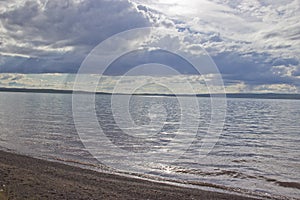 The sun`s rays make their way through the clouds and illuminate the lake