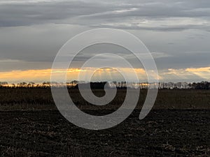 The sun`s rays penetrate through the clouds. The sun is approaching the sunset. Evening landscape in the countryside