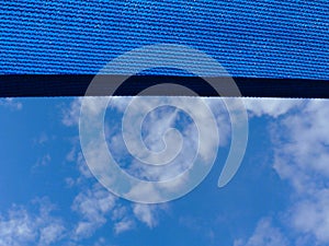 Sun sail. breathing blue fabric sun shade material spanning over terrace area. blue sky and cluds photo