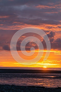 Sun sets on horizon over water creating beautiful coloured sky