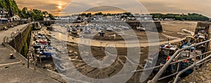 The sun sets over fishing boats and pleasure craft in Saundersfoot  harbour, Wales at low tide