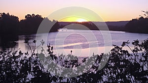 The sun sets over the Hawkesbury River at Windsor, west of Sydney, Australia. In the distance two fishing boats and the Blue