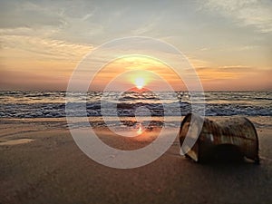 The sun sets on a wavy beach