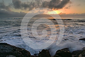 Sun setting above the horizon as viewed from Southern Breakwater Viewing Platform in Greymouth, New Zealand