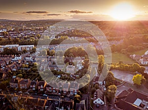 Sun setting with atmospheric effect over traditional British houses and tree lined streets.