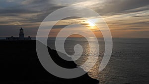 The Sun setting behind the lighthouse at Strumble Head, Pembrokeshire, Wales, UK.