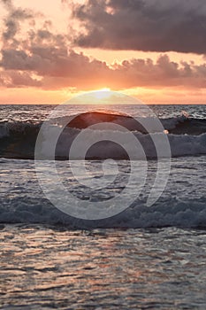 Sun setting behind the ocean with waves on the foreground