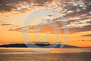 Sun is setting behind Skiathos island, view from Kastani Mamma Mia beach, island of Skopelos