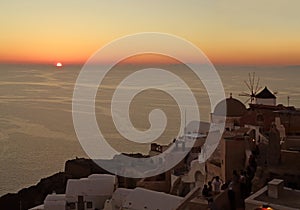 The sun setting on the horizon of Aegean sea, Oia village, Santorini island, Greece
