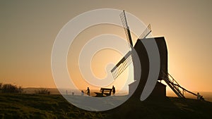 Sun setting on the horizon behind a traditional wooden windmill at sunset