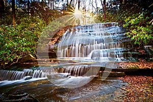 Sun setting over Grogan Creek Falls or Falls on Grogan Creek located in Pisgah National Forest near Brevard NC