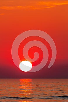 Sun setting over ocean, red, orange sky - background