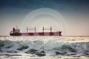 Sun setting at the sea with sailing cargo ship